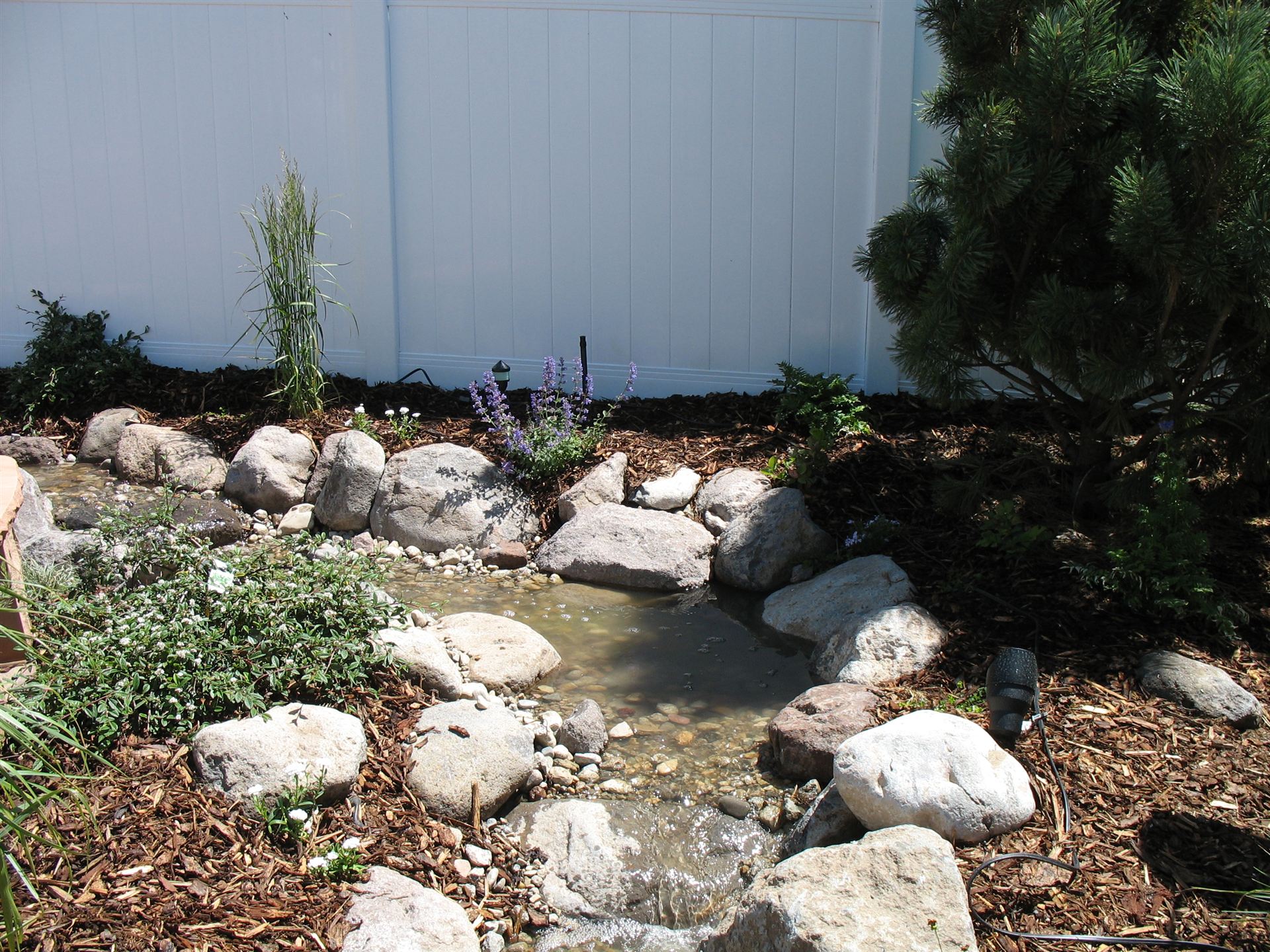 Close view of a rock stream feature with wildflowers