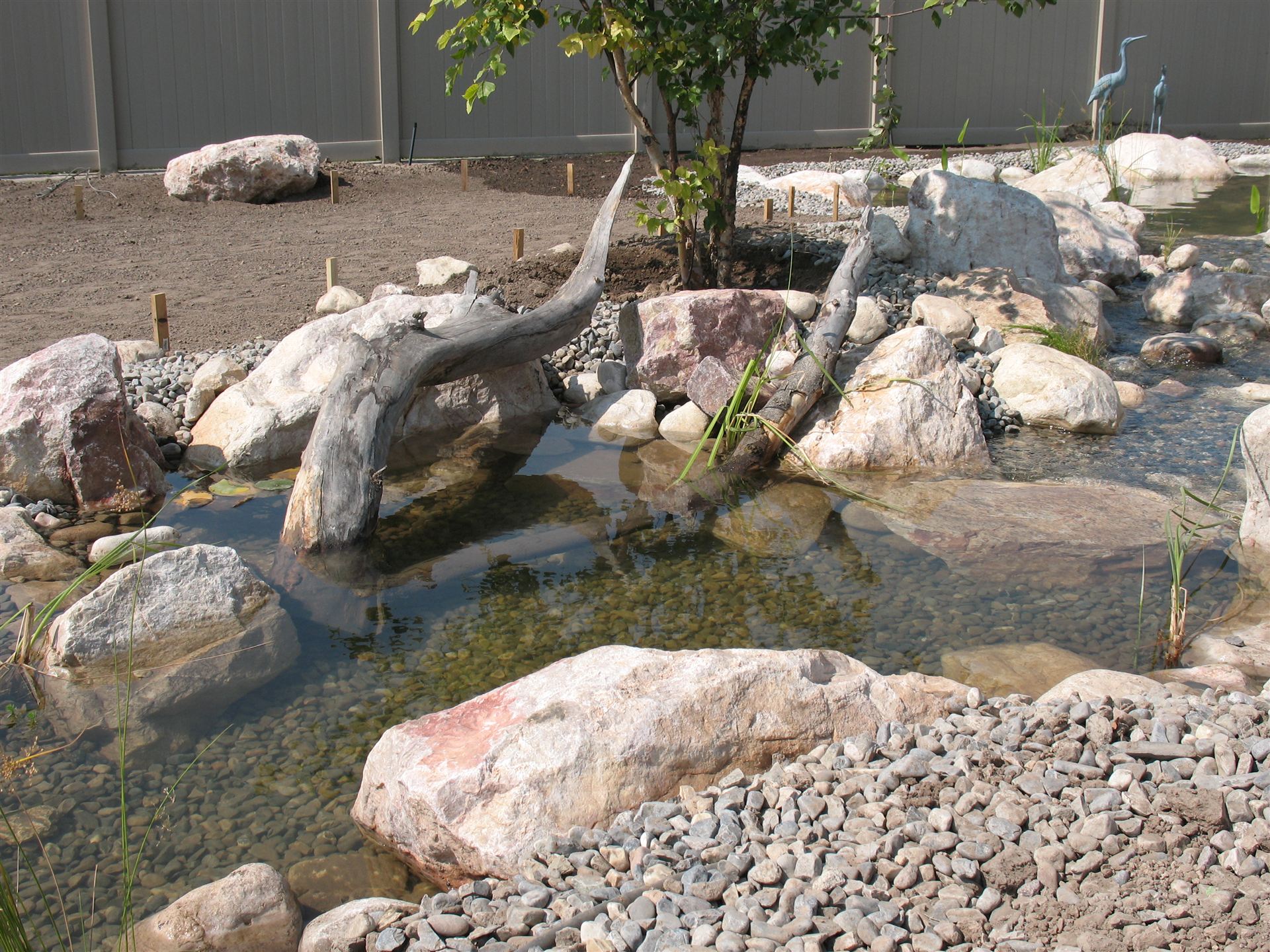 Driftwood waterfall feature flowing into a pond