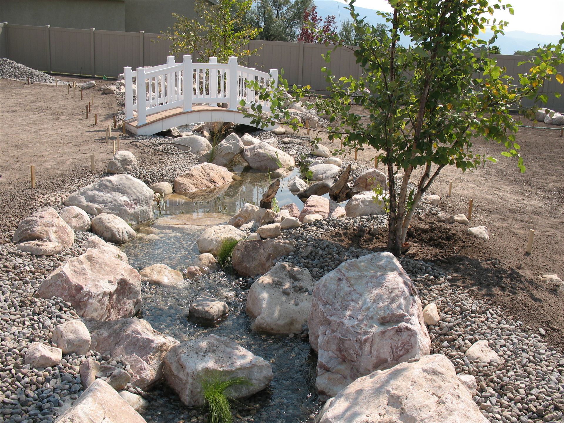Pond and stream feature under construction with driftwood accents